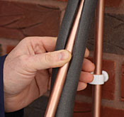 A technician insulating a copper pipe