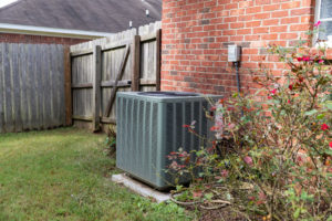 An air conditioning unit installed outside next to a home's fence
