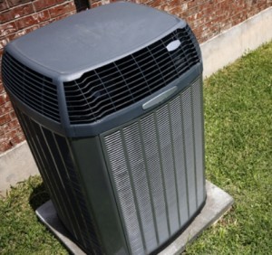 heat pump unit in grass lawn next to red brick house