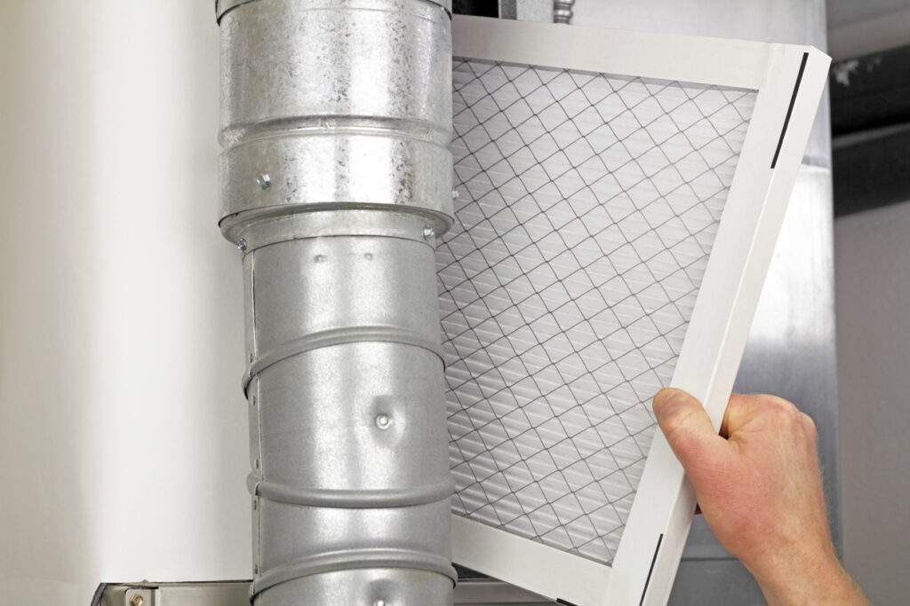 Man replacing disposable air filter in residential air furnace..